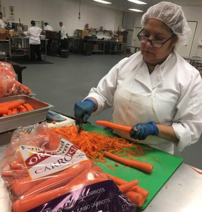 Veestro employees do all prep work manually, like this employee above who is peeling organic carrots.